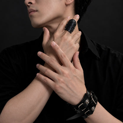 黒いシャツの男性モデルが指に着けたアーマーリング、月詠みの指輪 深黒。手首には革のブレスレット